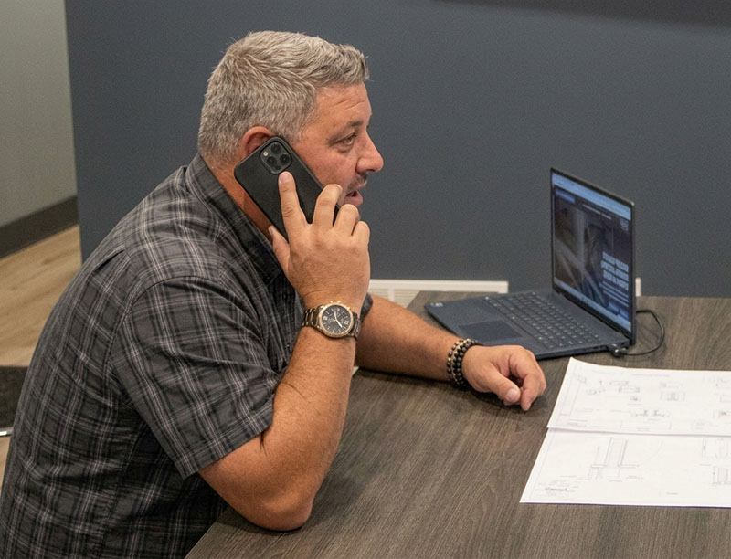 Ray taking a dealer call at his desk while reviewing build drawings